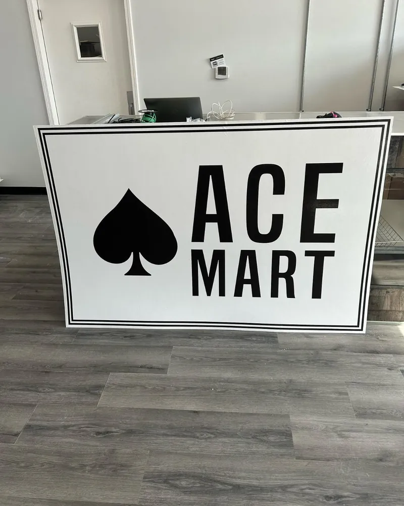 Black and white Ace Mart sign panel with a spade logo, before installation