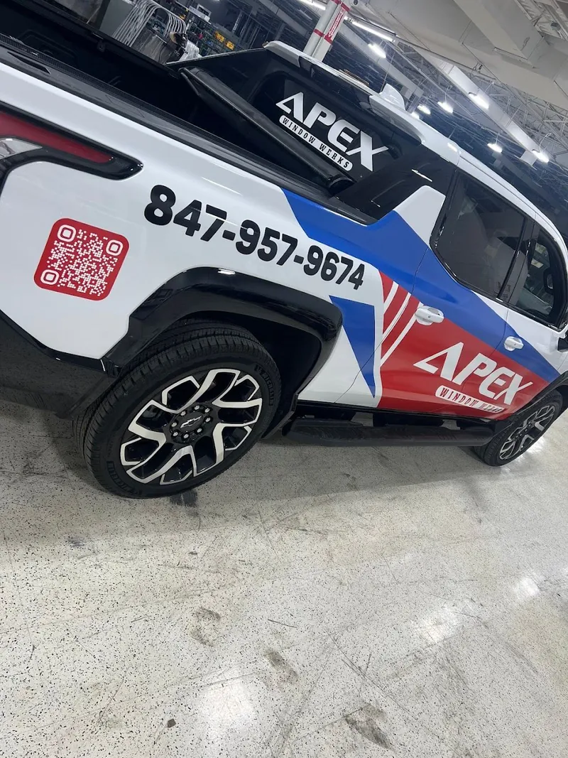 Close-up of a white pickup with APEX Window Werks graphics, phone number and a red QR code on the side