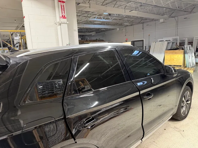 Black SUV with dark tinted side windows parked inside the shop