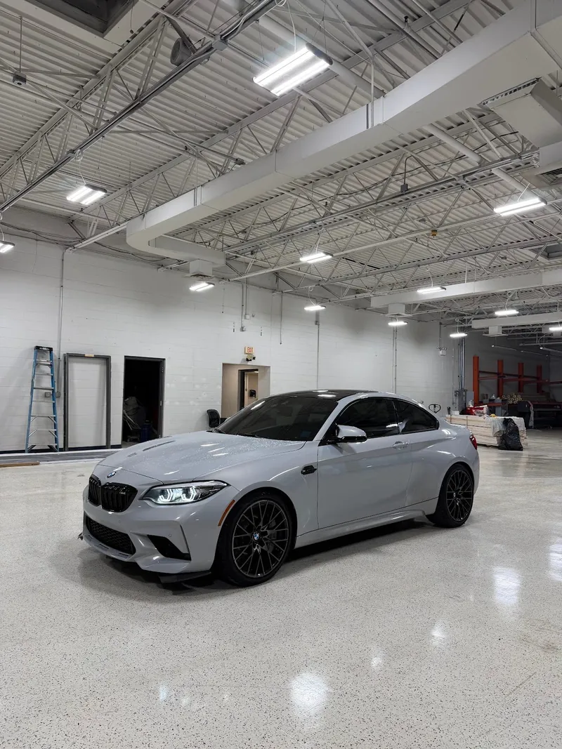 Gray BMW M2 coupe with tinted windows parked in the shop