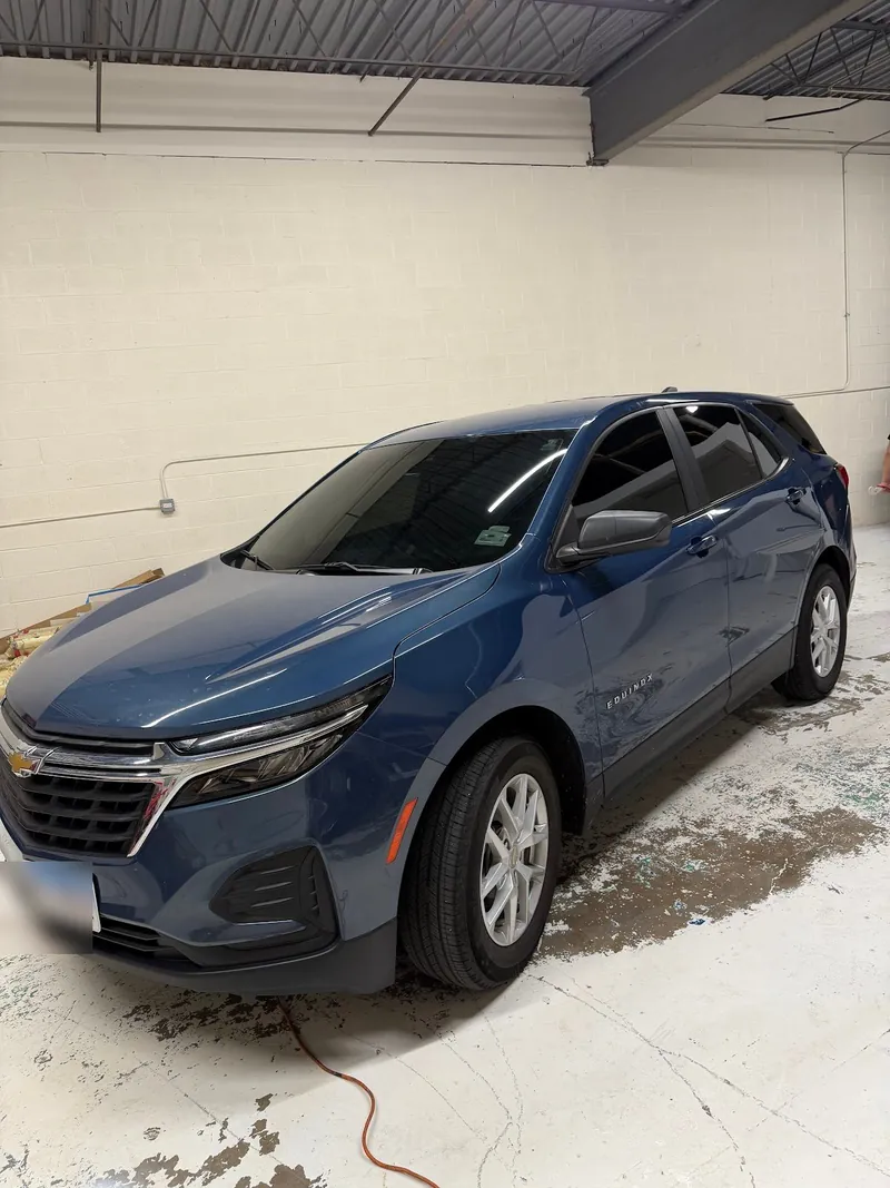 Front three-quarter view of a blue Chevrolet Equinox with tinted windows in the shop
