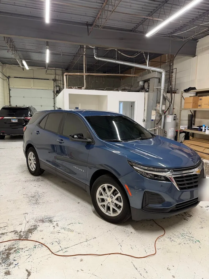 Blue Chevrolet Equinox with tinted windows in the shop bay