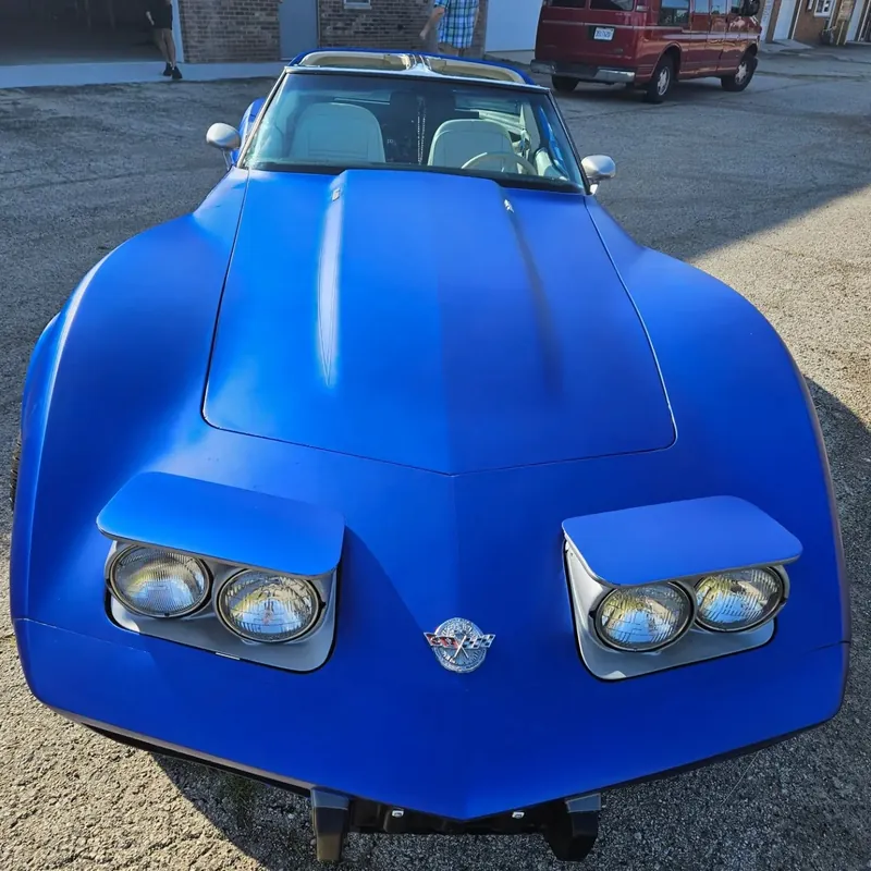 Front of a classic Corvette with pop-up headlights, wrapped in matte chrome blue