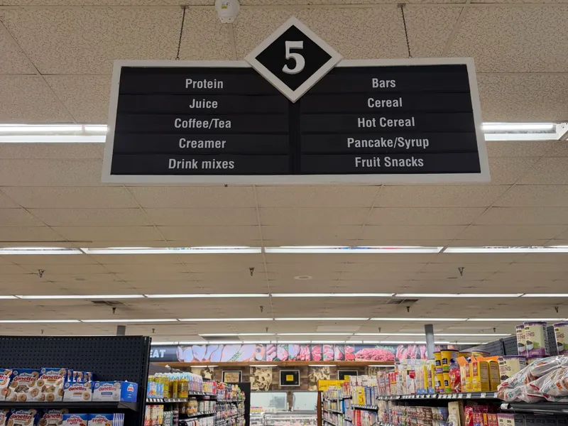 Black double-sided hanging aisle sign numbered 5, listing protein, juice, cereal and other products