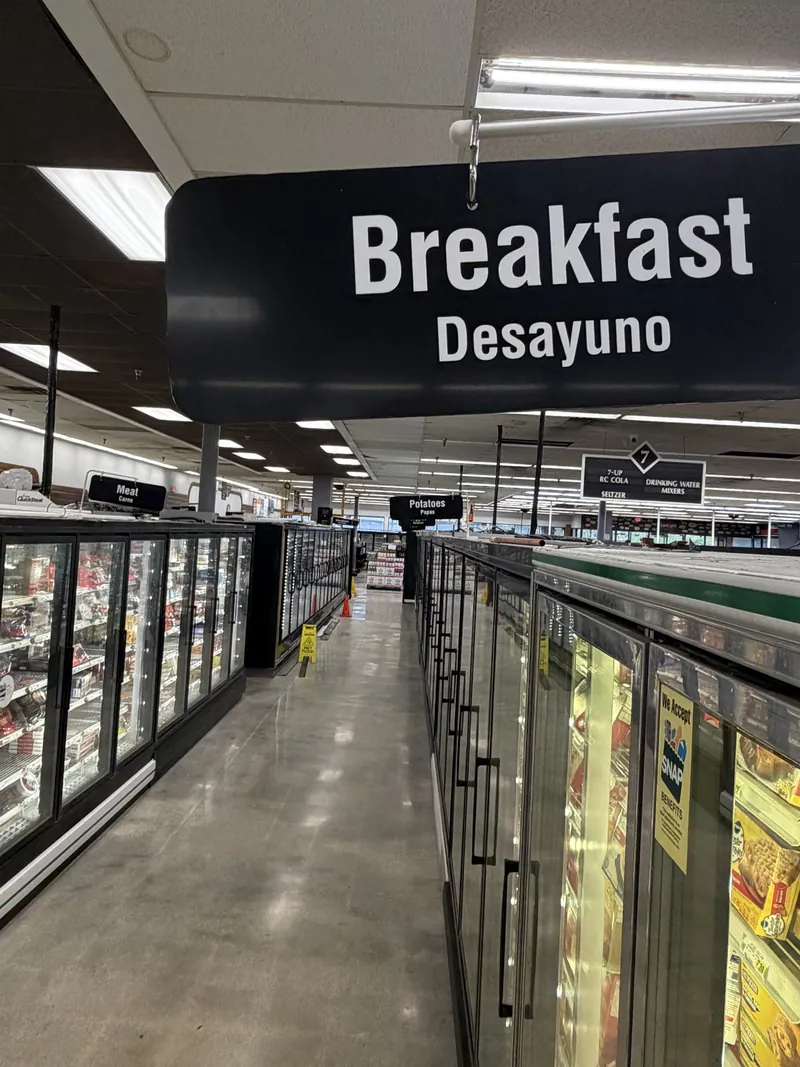 Black hanging sign reading Breakfast and Desayuno above a grocery store aisle