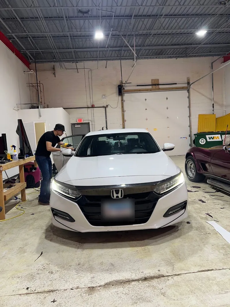 Installer working on the windows of a white Honda Accord in the shop