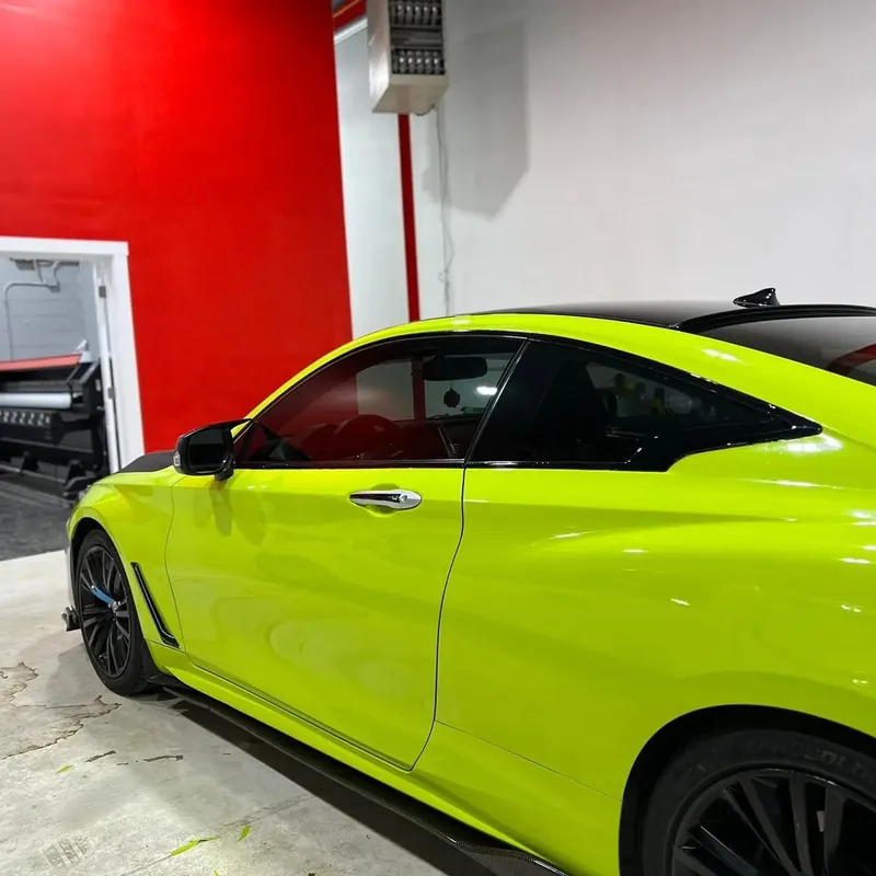 Infiniti Q60 coupe wrapped in bright lime green, parked in the shop
