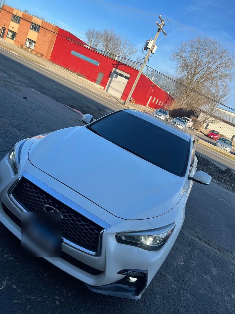 White Infiniti SUV with tinted windows parked outside on a sunny day