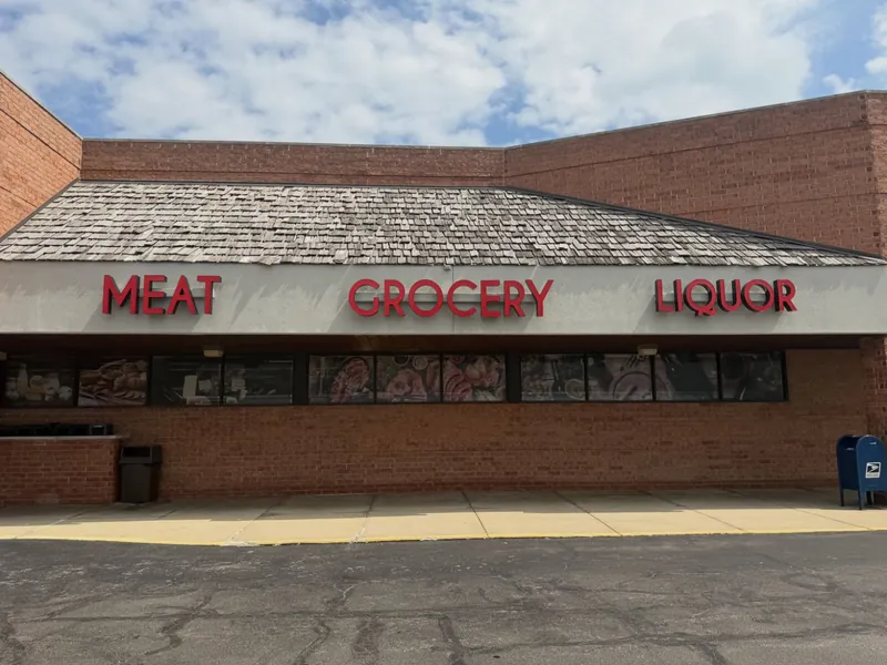 Supermarket façade with red letters reading Meat, Grocery and Liquor above printed window graphics