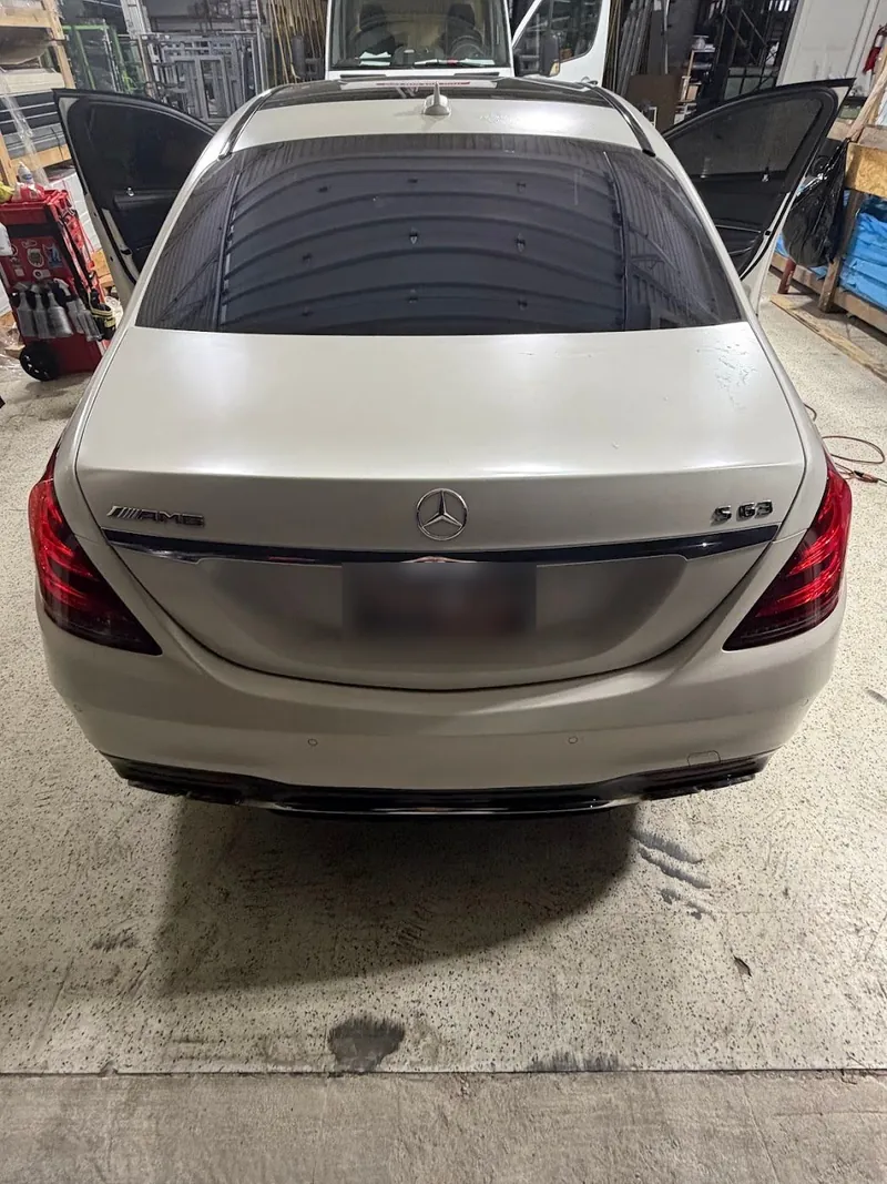 Rear view of a white Mercedes-Benz S-Class with a tinted rear window in the shop