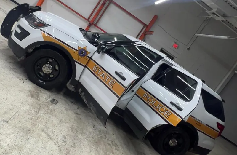 State police SUV with doors open inside a shop during a window tint install