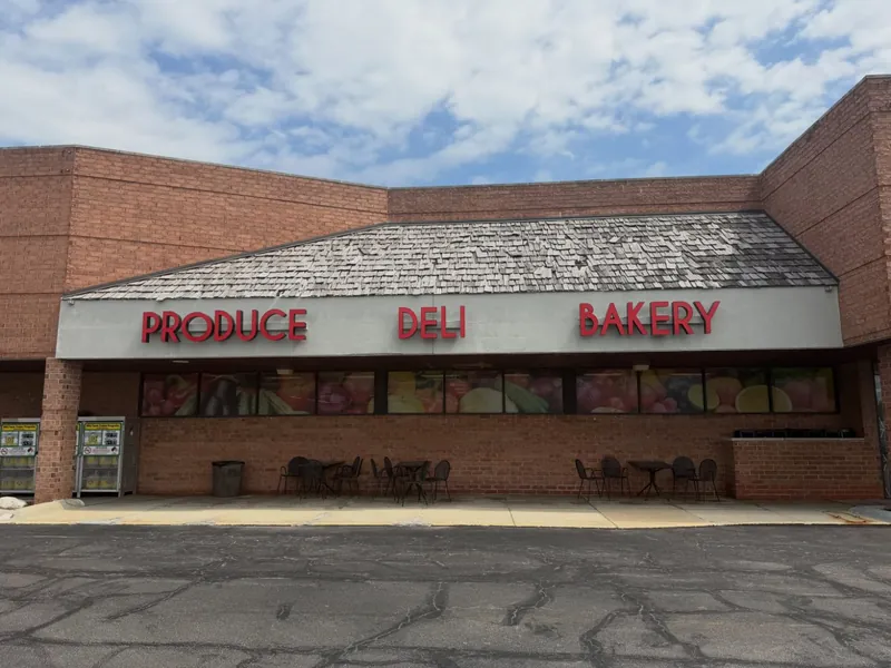 Supermarket façade with red letters reading Produce, Deli and Bakery above printed window graphics