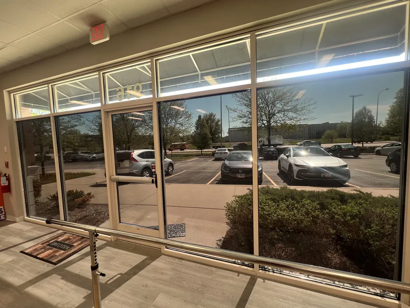 Inside a commercial space looking out through tinted storefront windows and a glass door to a parking lot