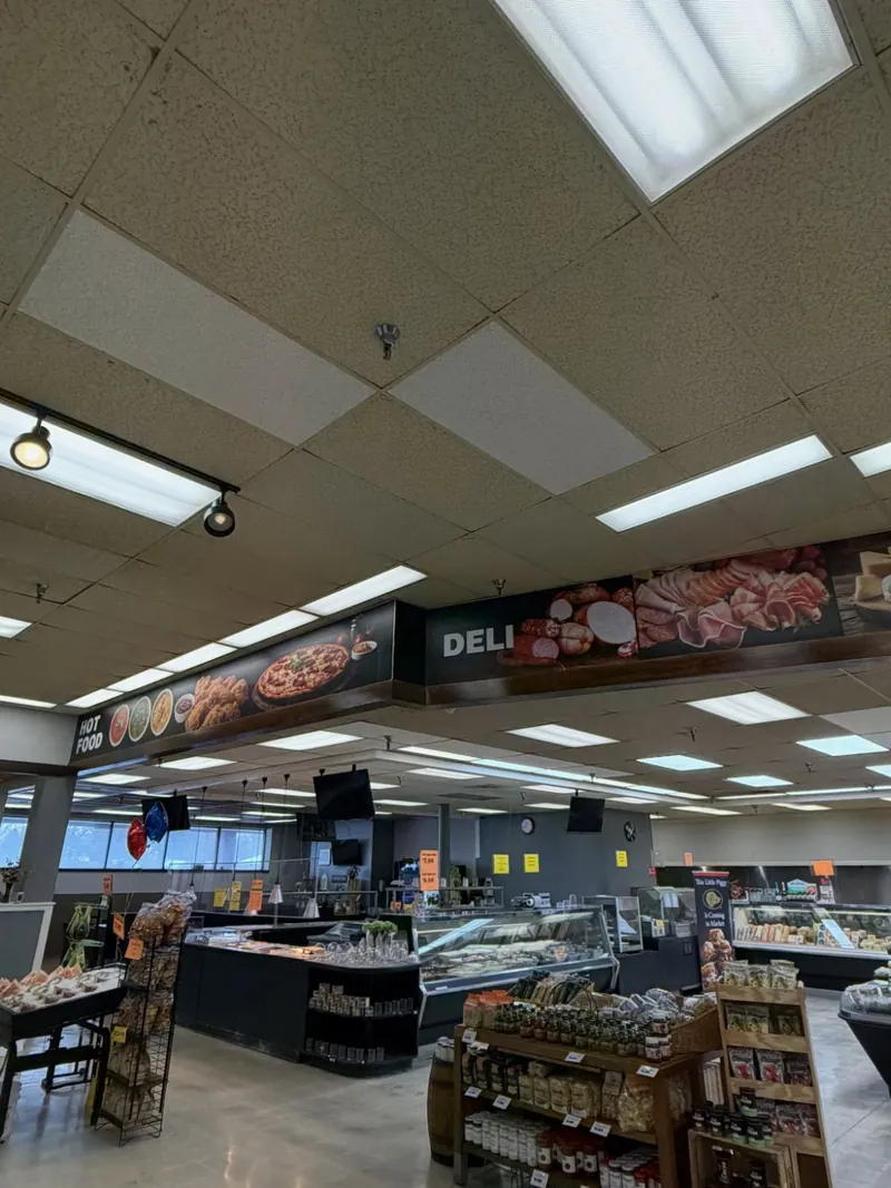 Supermarket deli counter under a long printed banner of deli food photography