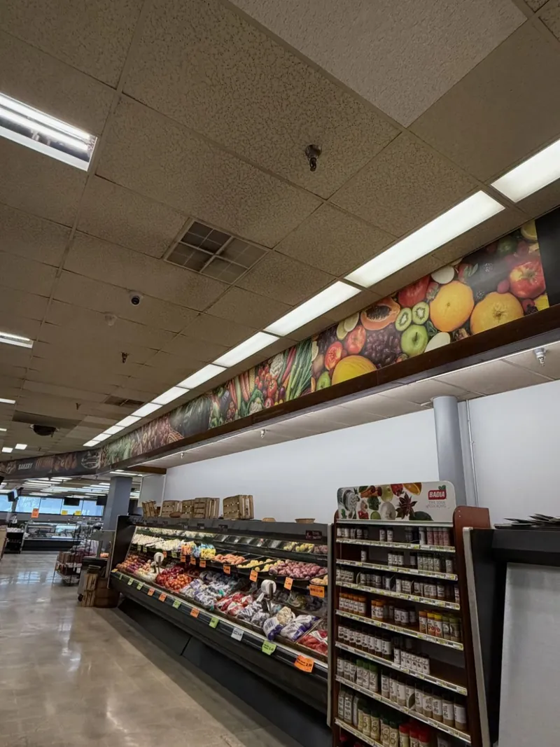Long printed fruit and vegetable banner above a supermarket produce section