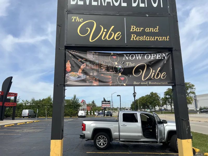 Now Open banner for The Vibe bar and restaurant hung below its pylon sign panel