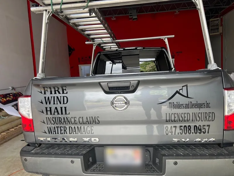 Gray Nissan Titan tailgate lettered with fire, wind, hail, insurance claims and water damage services and a phone number