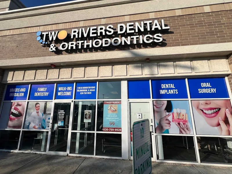 Two Rivers Dental & Orthodontics storefront with blue service headers and smiling patient photos covering the windows