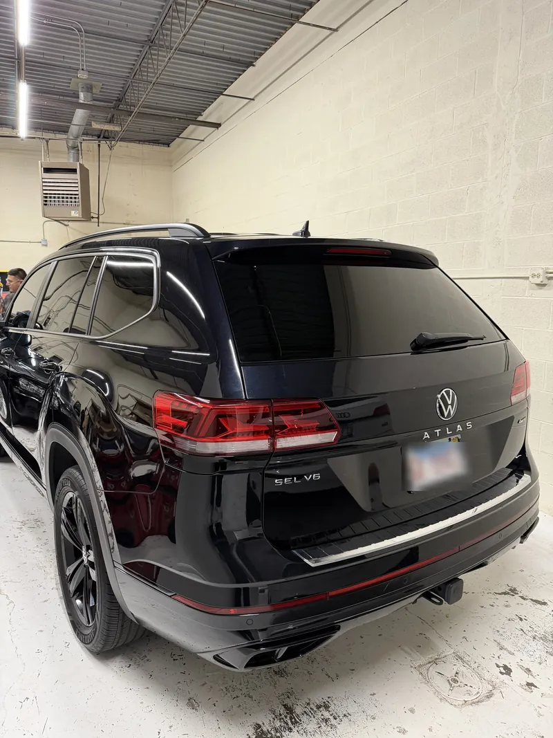 Black Volkswagen Atlas with dark tinted rear and side windows inside a shop