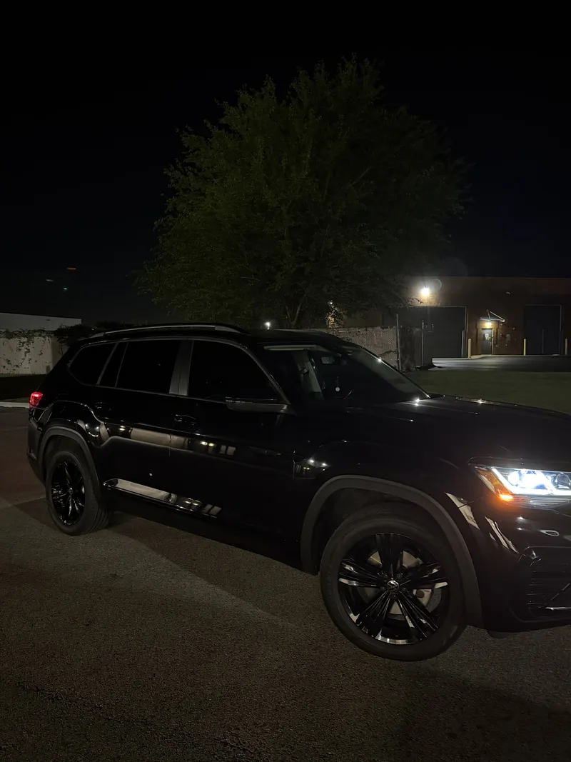 Black Volkswagen Atlas with tinted windows parked at night under a single light