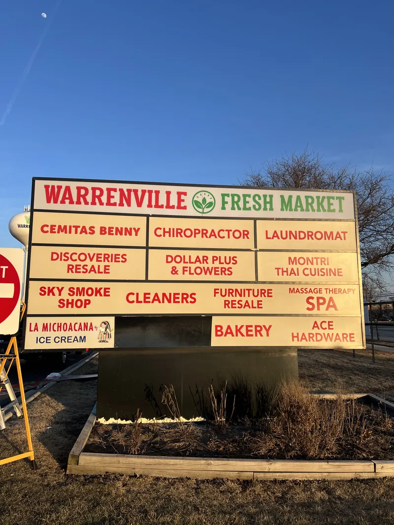 Multi-tenant pylon sign with Warrenville Fresh Market and red tenant panels for a laundromat, bakery, cleaners and other shops