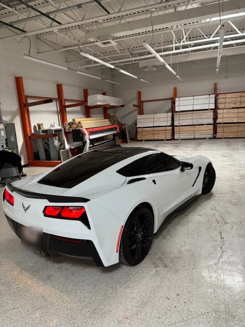 White Corvette with a black roof and tinted glass inside the shop