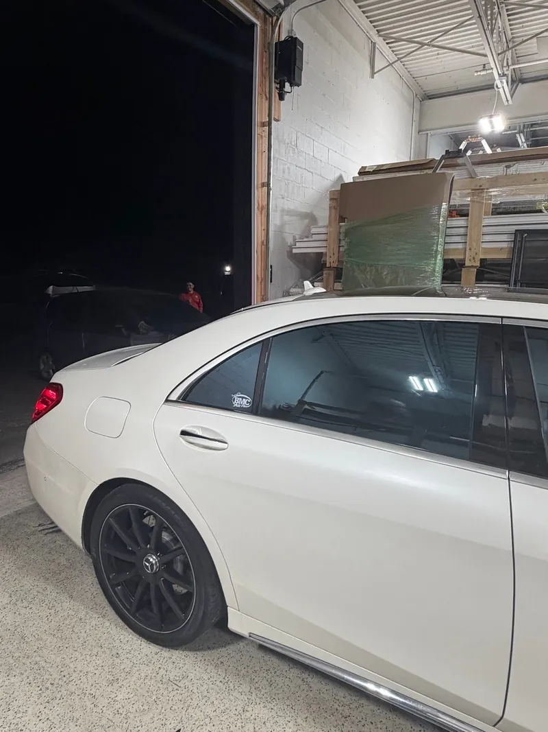 Side view of a white Mercedes-Benz sedan with dark tinted windows
